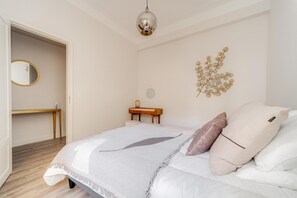 Een slaapkamer met een bed, nachtkastje en een spiegel aan de muur.