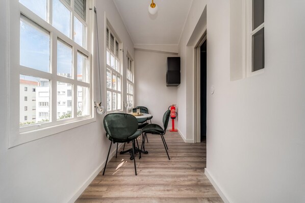 Un couloir étroit doté de grandes fenêtres, une table avec des chaises et un extincteur.