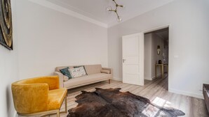 Un salon moderne avec un canapé beige, un fauteuil jaune et un grand tapis en cuir.
