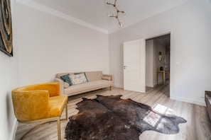 Een moderne woonkamer met een beige bank, een gele fauteuil en een groot leren vloerkleed.