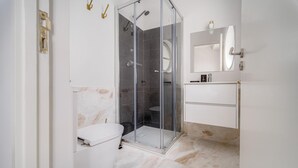 Un baño moderno con ducha envuelta en vidrio, inodoro blanco y tocador con espejo.