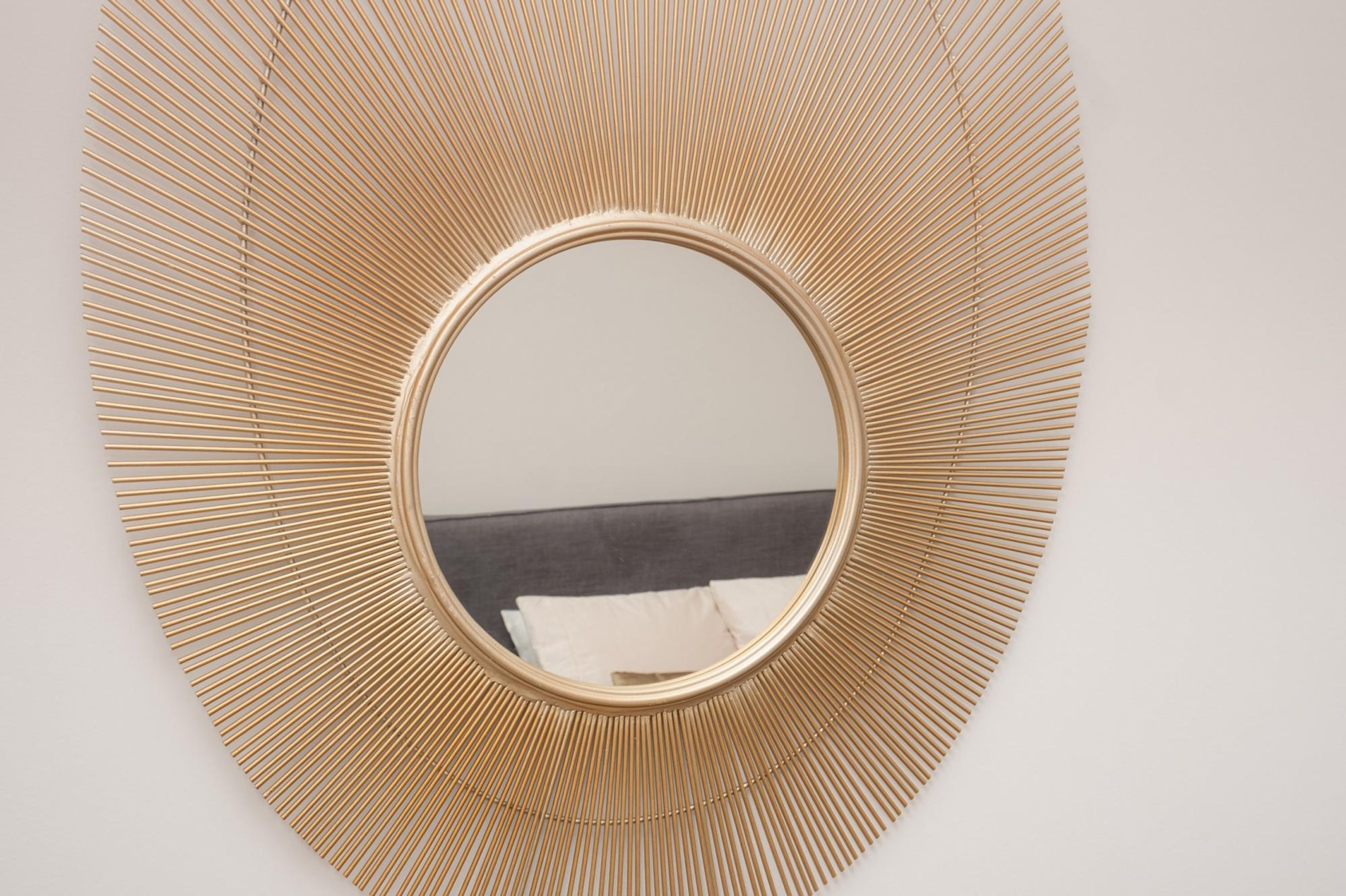 A round mirror with a gold frame on a white wall.