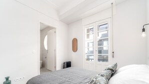 A bedroom with a bed, a radiator, a door, and a wall-mounted light fixture. - Nomad s By Sta Catarina Flats - 3bdr Family (Porto)