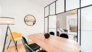 A modern dining area with a wooden table, black chairs, a yellow chair, a floor lamp, and a decorative item on the table. - Nomad s By Sta Catarina Flats - 3bdr Family (Porto)