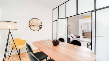 Uma área de jantar moderna com uma mesa de madeira, cadeiras pretas, uma cadeira amarela, um abajur e um objeto decorativo sobre a mesa.