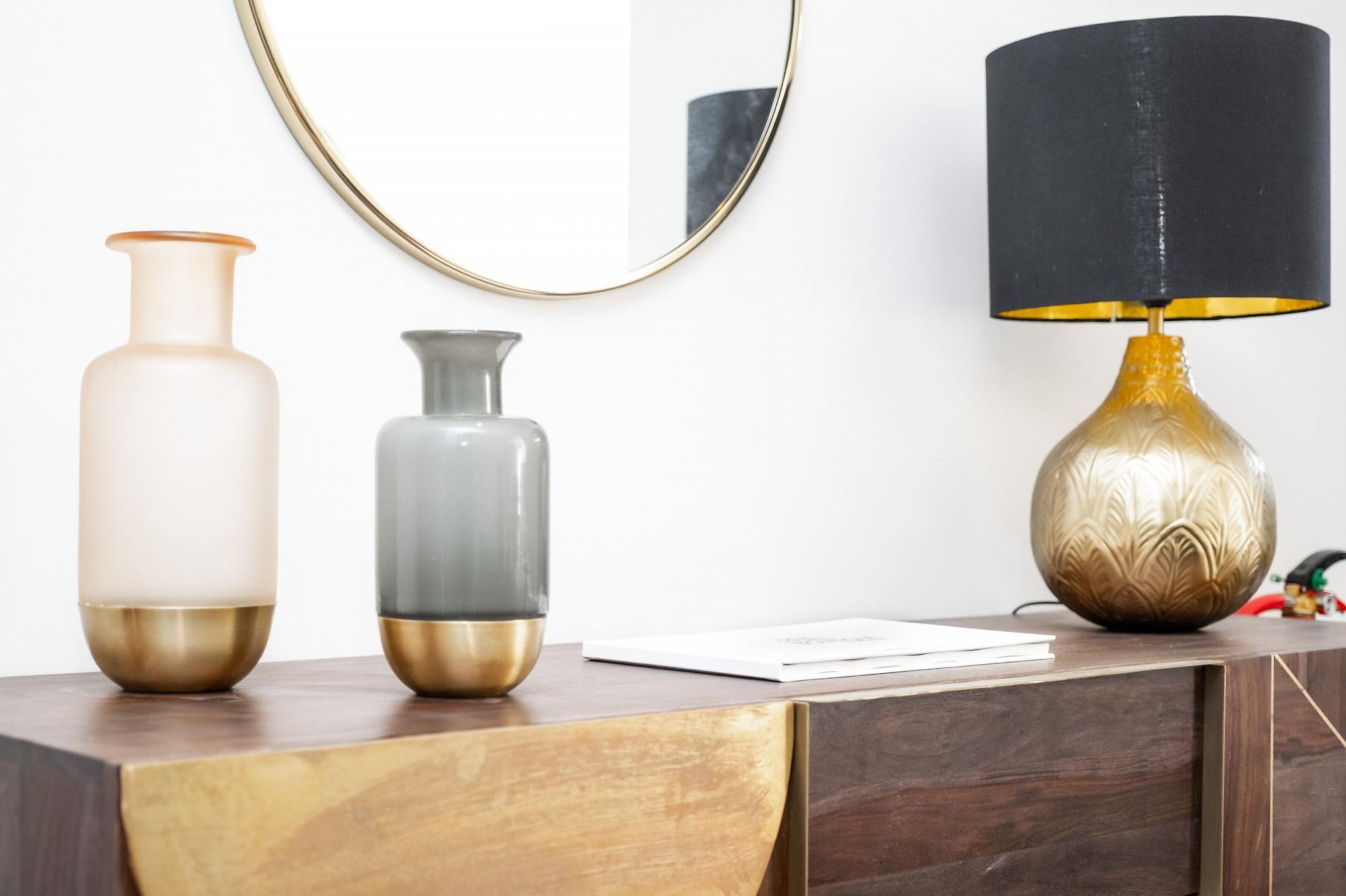 A wooden desk with two vases and a lamp.