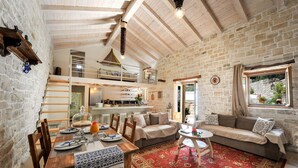 A rustic interior with a dining area, a sofa, and a kitchen. - Leonora House With Private Pool Close to Gaios (Paxos)