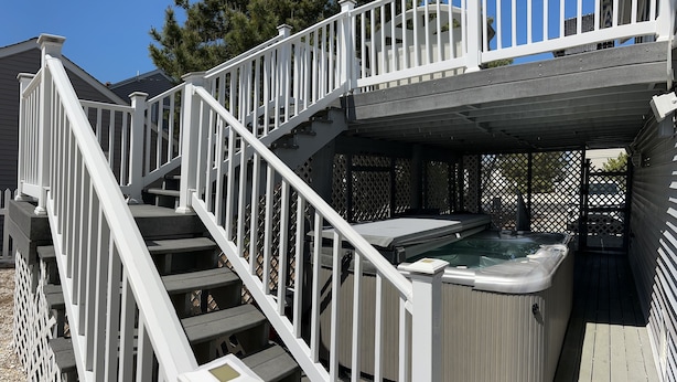 Un jacuzzi con terraza de madera y barandas blancas.