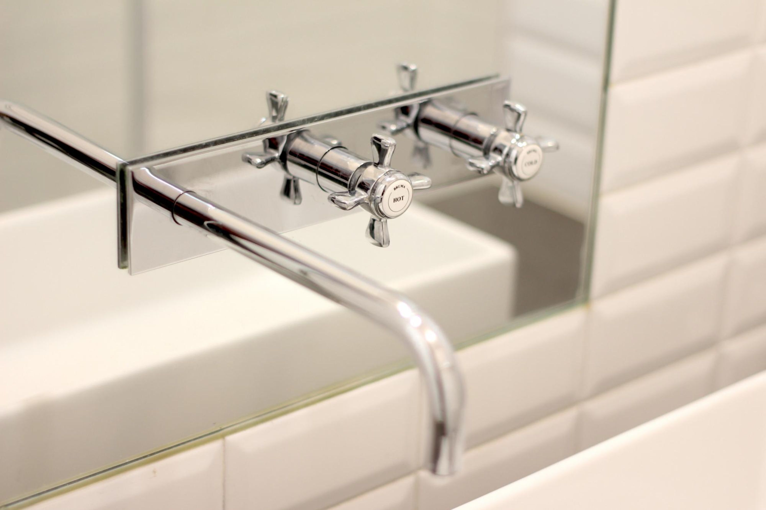 A modern bathroom with a glass-enclosed sink and chrome fixtures.