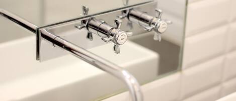 A modern bathroom with a glass-enclosed sink and chrome fixtures.