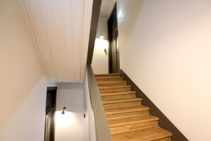A wooden staircase with a handrail, white walls, and a door at the top. - Nomad s Downtown Lisbon - 3bdr Charming Memory (Lisbon)