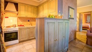 A kitchen with wooden cabinets, a stove, and a sink. There is a fruit bowl on the counter and a mirror on the wall. - Theodora Villa - 2 BR Tranditional House Close to Gaios Town (Paxos)