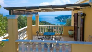 A balcony with a table and chairs, overlooking a coastal view. - Theodora Villa - 2 BR Tranditional House Close to Gaios Town (Paxos)