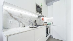 A modern kitchen with white cabinetry, a marble backsplash, stainless steel appliances, and a built-in microwave. - Nomad s Formosa Comfort - 1bed Porto (Porto)