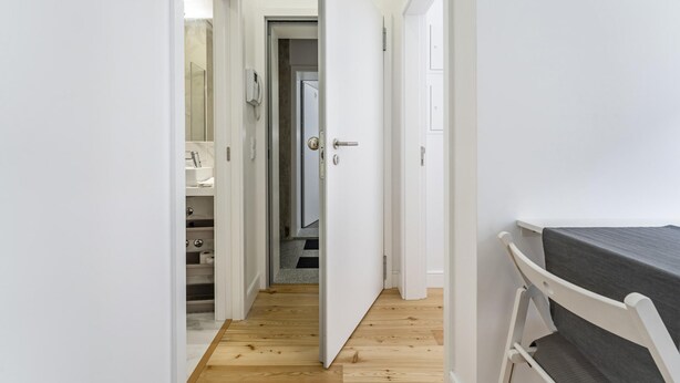 A narrow hallway with wooden flooring leading to a bathroom with a white sink and a mirror. - Nomad s Formosa Comfort - 1bed Porto (Porto)