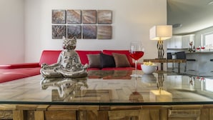 Una sala de estar moderna con una mesa de centro de vidrio, un sofá rojo y arte abstracto en la pared.
