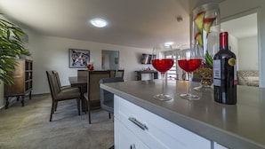 Una cocina moderna con comedor, que incluye una barra con copas de vino y una botella.