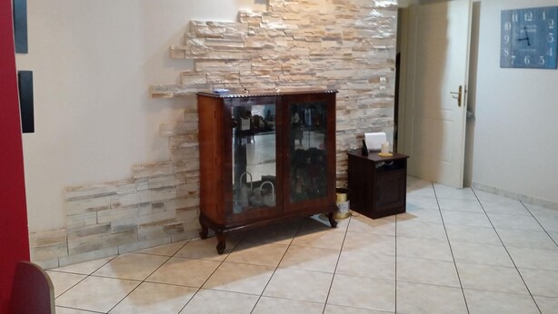 A room with a stone wall, a wooden cabinet, and a clock on the wall. - Kallithea Comfy 1 in Kalithea (Kallithea)