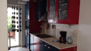 A kitchen with red and blue cabinets, a coffee maker, and a chalkboard menu. - Kallithea Comfy 1 in Kalithea (Kallithea)