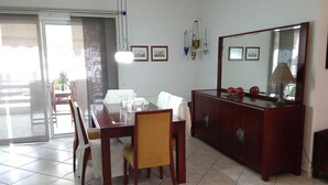 A dining area with a wooden table and chairs, a cabinet with a mirror, and a window with blinds. - Kallithea Comfy 1 in Kalithea (Kallithea)