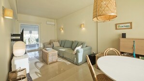 Ein modernes Wohnzimmer mit einer Couch, einem Esstisch und einer Pendelleuchte.