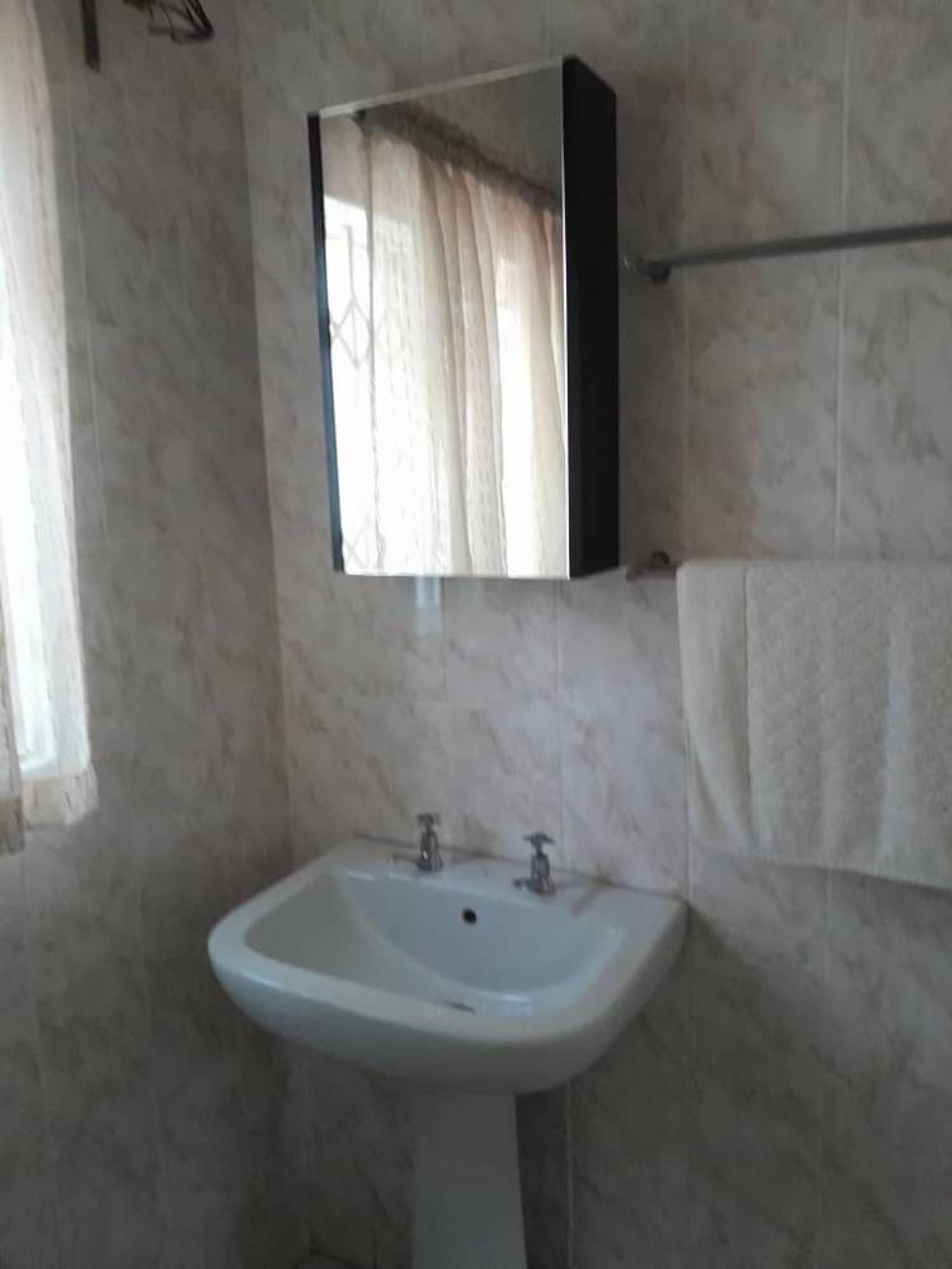 A bathroom with a white sink, a mirror, and a towel hanging on the wall.