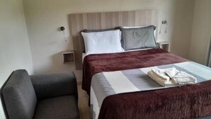 Een hotelkamer met een bed, een stoel en een nachtkastje.