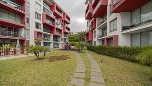 Ein modernes Mehrfamilienhaus mit roten Balkonen und einem Innenhof mit Spielplatz.