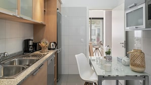 Eine moderne Küche mit Granit-Arbeitsplatten, Edelstahlgeräten und einem Essbereich mit einem Glastisch und weißen Stühlen.