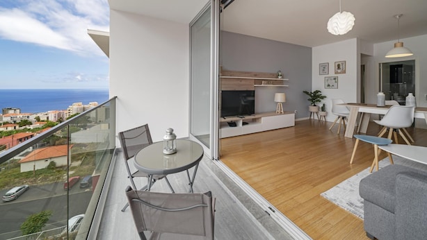 Eine moderne Wohnung mit Balkon und Meerblick, einem Essbereich und einer Küche mit Holzboden.