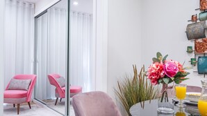 Ein stilvoller Essbereich mit einem runden Tisch, rosa Stühlen und einer Vase mit Blumen.