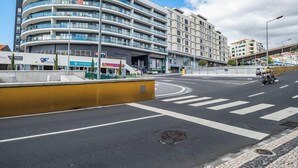 Ein mehrgeschossiges Gebäude mit einer gewölbten Fassade, einer Fußgängerüberweg und einer Straße mit einem Motorrad.