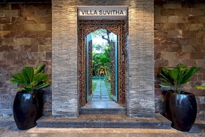 Enter through the grand entrance with an ornate archway, featuring the villa's name prominently displayed above.