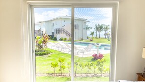 A bedroom with a large sliding glass door leading to a pool area, a bed, and a nightstand. - Residences C2-pbb in Chame (Punta Chame)