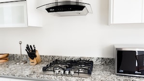 A modern kitchen with a gas stove, stainless steel appliances, and white cabinetry. - Residences C4-1c in Chame (Punta Chame)