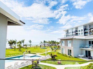 A modern hotel with a pool, outdoor seating, and a view of the ocean.