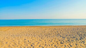Een strand met helderblauw water en een zandstrand.