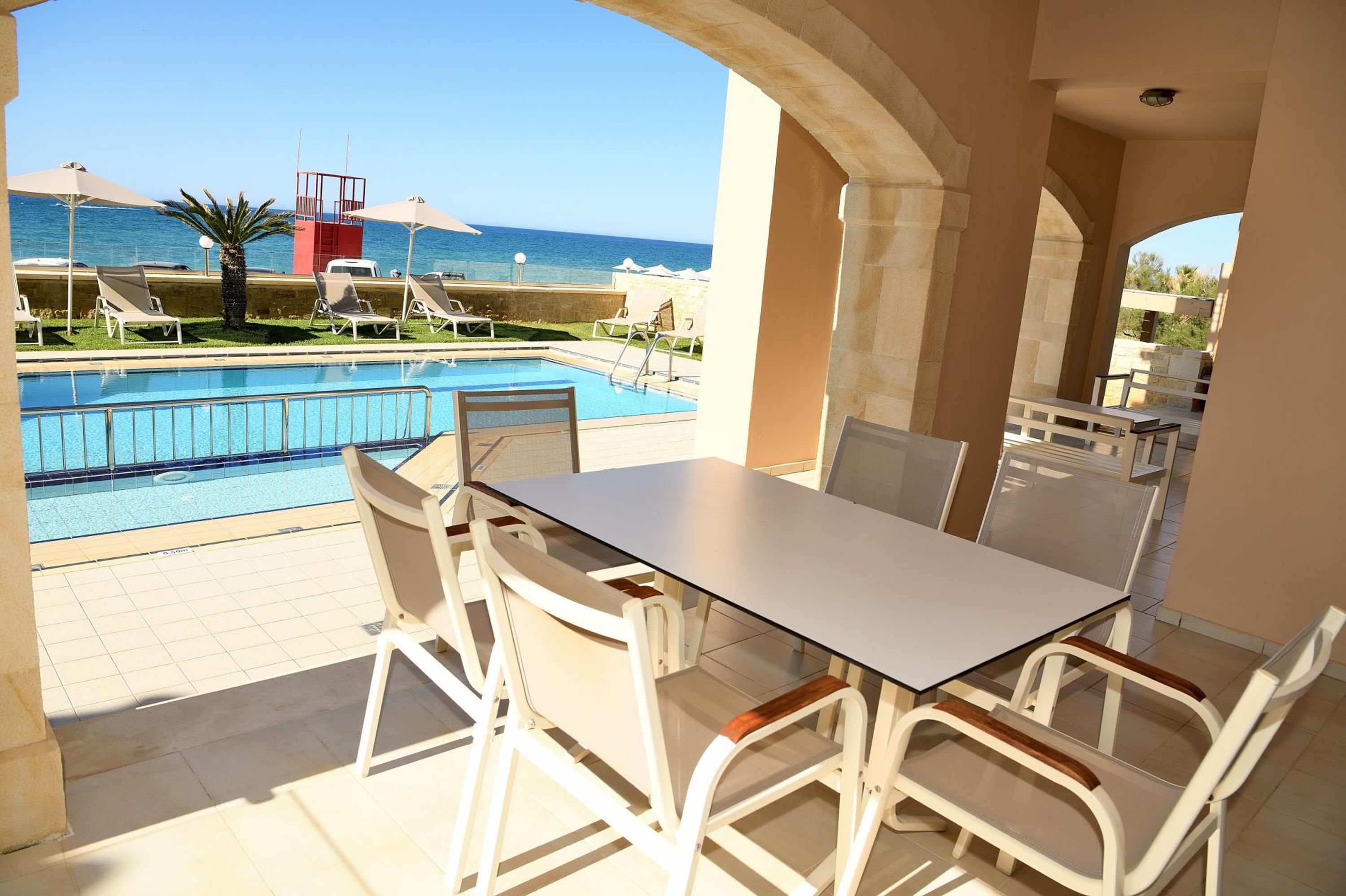 Un espace aménagé au bord de la piscine, avec une table et des chaises, offrant une vue sur la piscine et la mer.