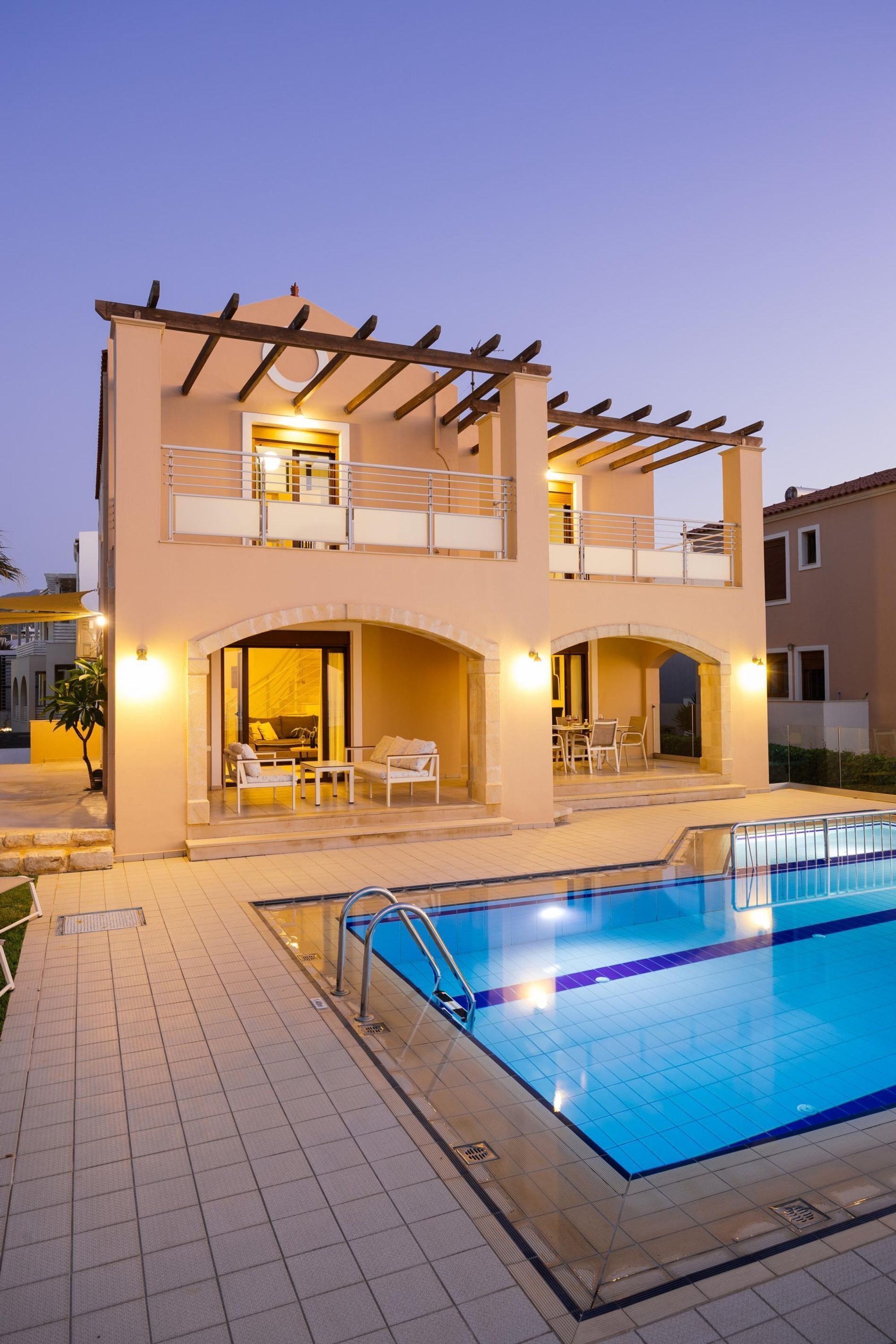 Un bâtiment à deux étages doté d’une piscine, d’un espace extérieur aménagé et d’une pergola.