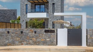Eine moderne Villa mit Natursteinfassade, einem Balkon und einem geschlossenem Eingangsbereich.