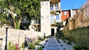 A narrow pathway leading to a building with stone walls and balconies.