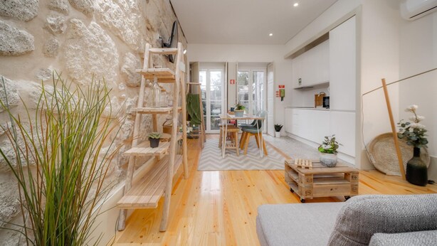 A modern living room with a stone wall, wooden furniture, and a dining area with a view.