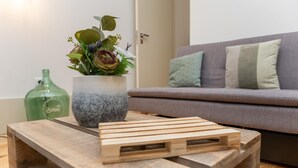 A wooden coffee table with a potted plant and a bottle on it.