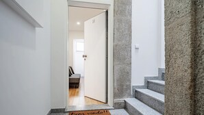 A hallway with a doormat reading "Bem vindo!" leading to a room with a bed and a window. - Nomad s Formosa Harmony - 1bed Porto (Porto)