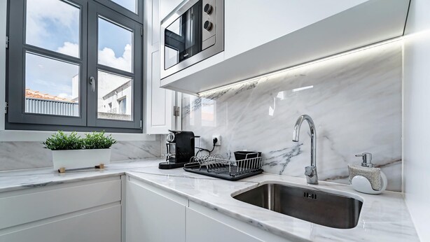 A modern kitchen with a marble countertop, a stainless steel sink, a coffee machine, and a dish rack. - Nomad s Formosa Harmony - 1bed Porto (Porto)