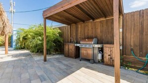An outdoor patio with a wooden pergola, a barbecue grill, and a water hose. - Turibana Plaza Suite 10 (Noord)