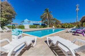 Relax by the pool surrounded by lush greenery and comfortable lounge chairs.