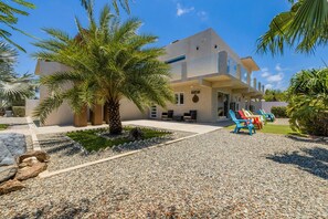 A modern two-story building with a flat roof, a covered patio area with outdoor seating, and a gravel driveway. - Koyari Modern Condos 2 (Noord)