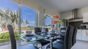 Een moderne eetruimte met een glazen tafel, zwarte stoelen en uitzicht op het buitengebied.