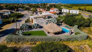 Een moderne villa met een zwembad, omgeven door weelderige begroeiing en een helder uitzicht op de oceaan.